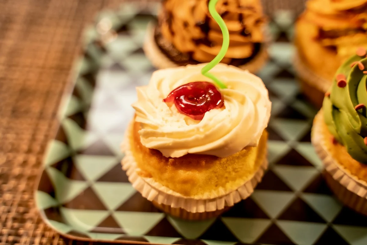 Representative cupcake topped with piped frosting and a red cherry