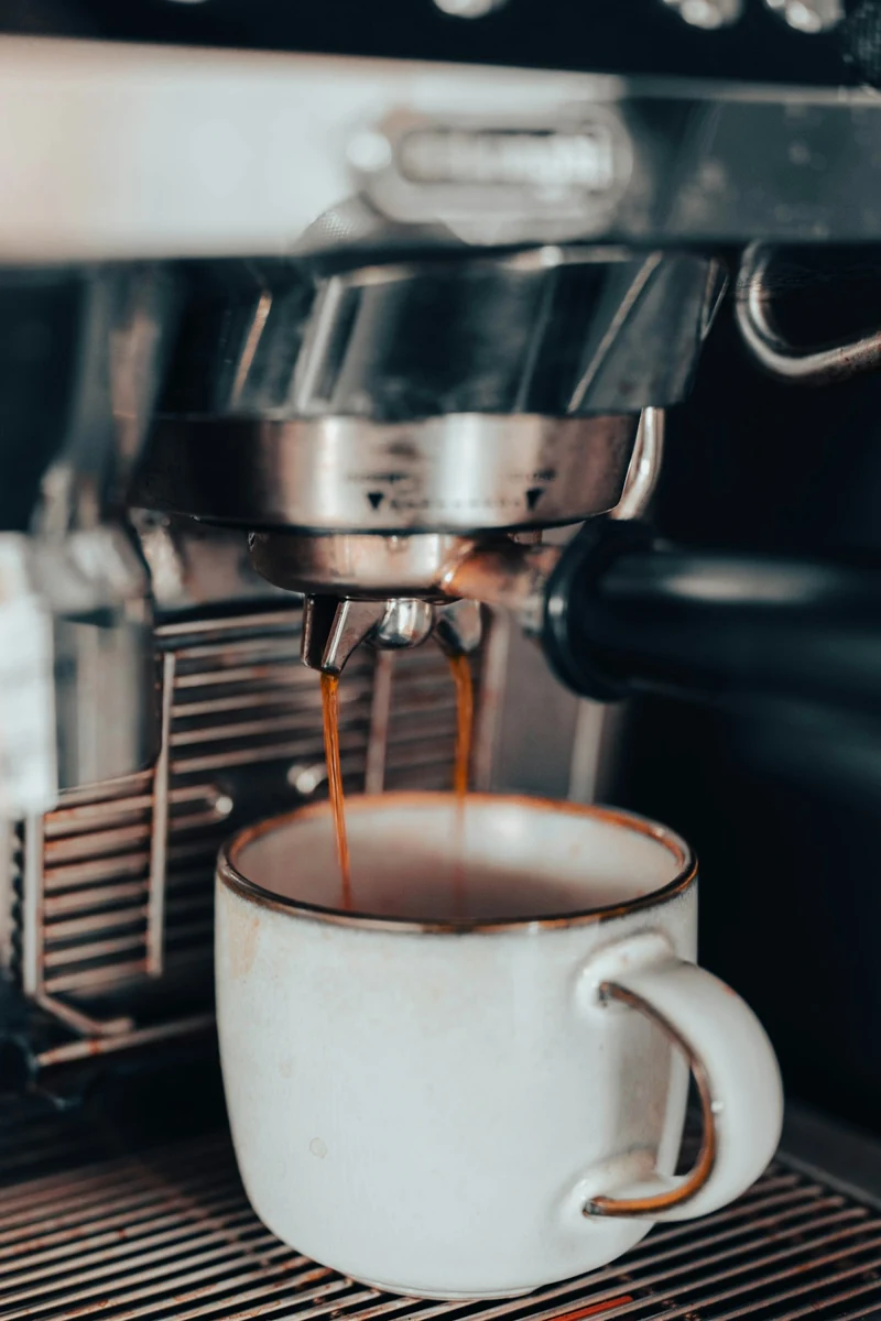 Representative photo of espresso pouring from a coffee machine into a ceramic cup